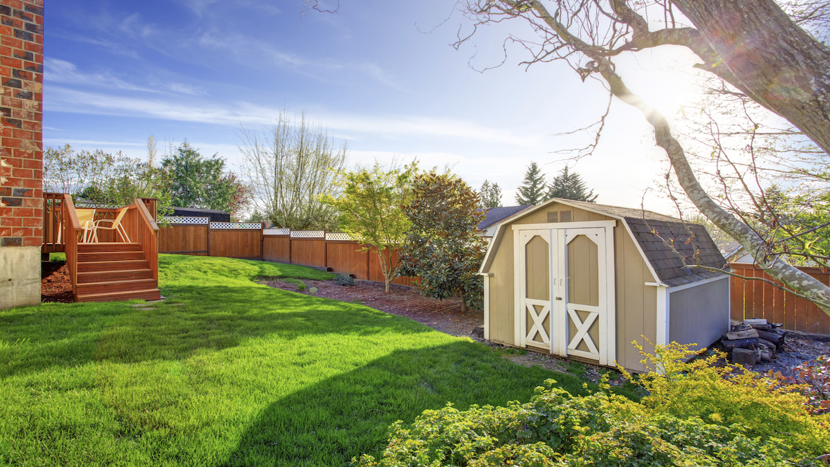 Fenced backyard with wooden walkout deck and small shed