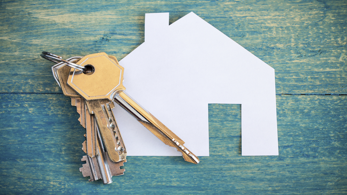 House icon and keys on wooden background