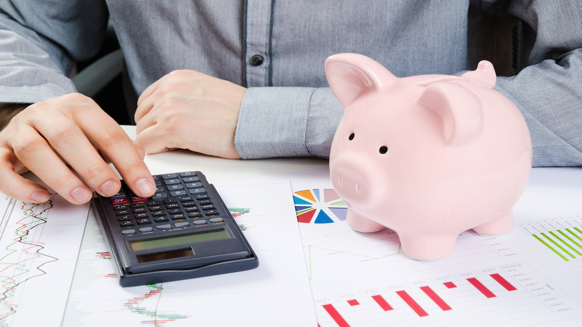 Man calculates money. Piggy bank and business documents on desk