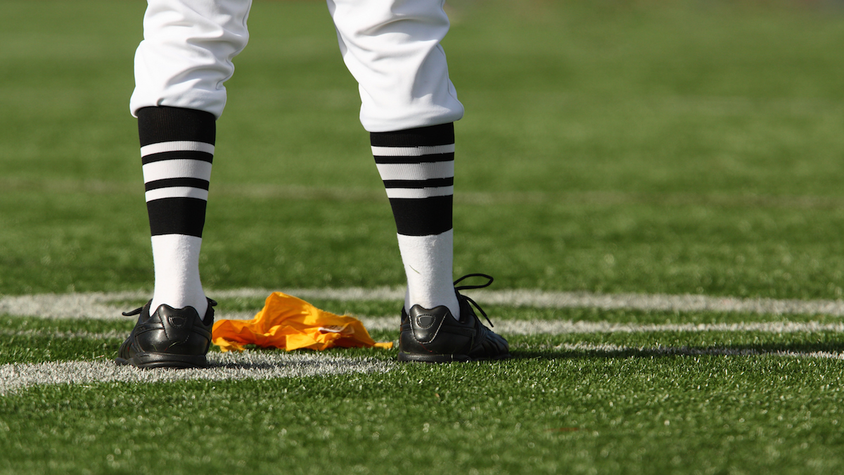 Close up detail of football referee's legs after a yellow penalty flag has been thrown.