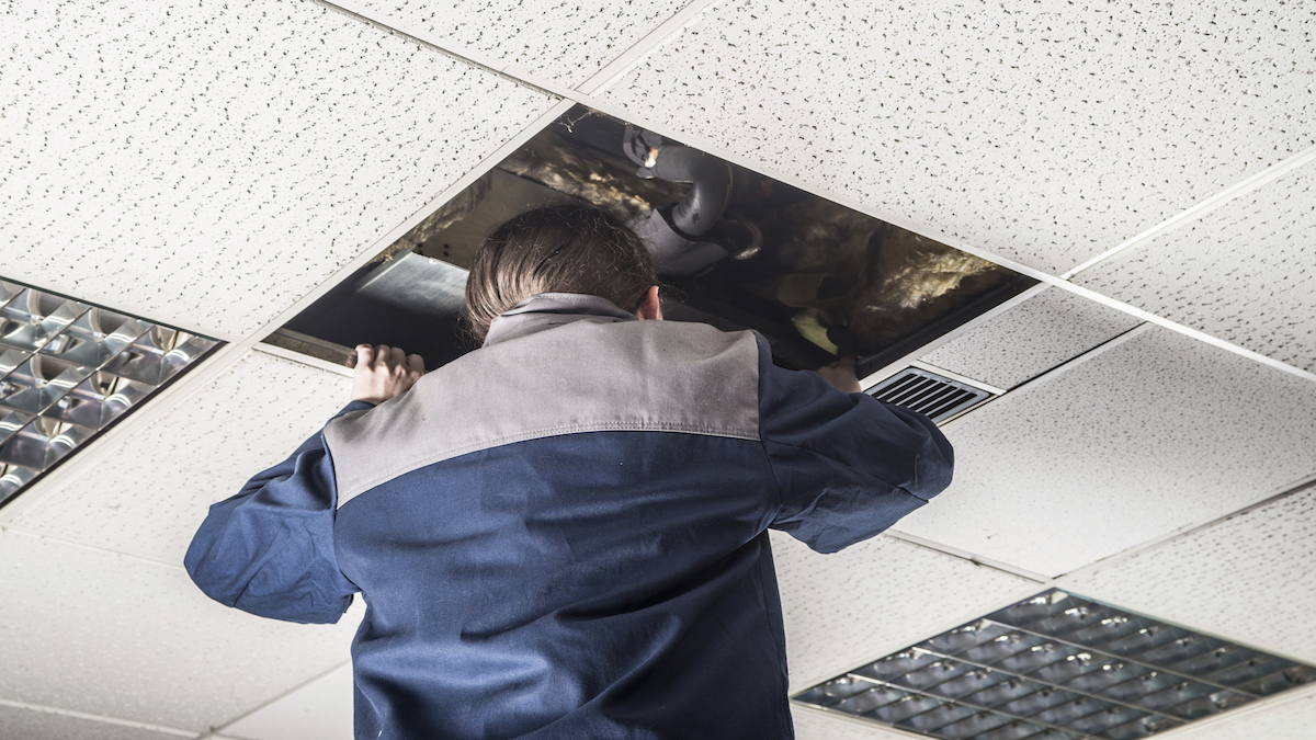 man looking up the ceiling, checking and repairing